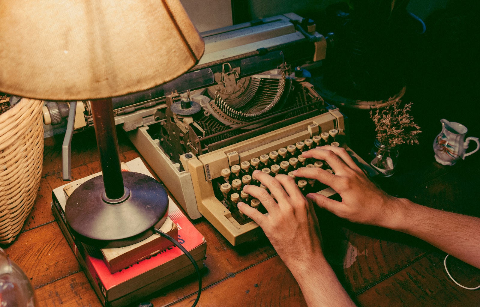 Hands on typewriter with lamp and books