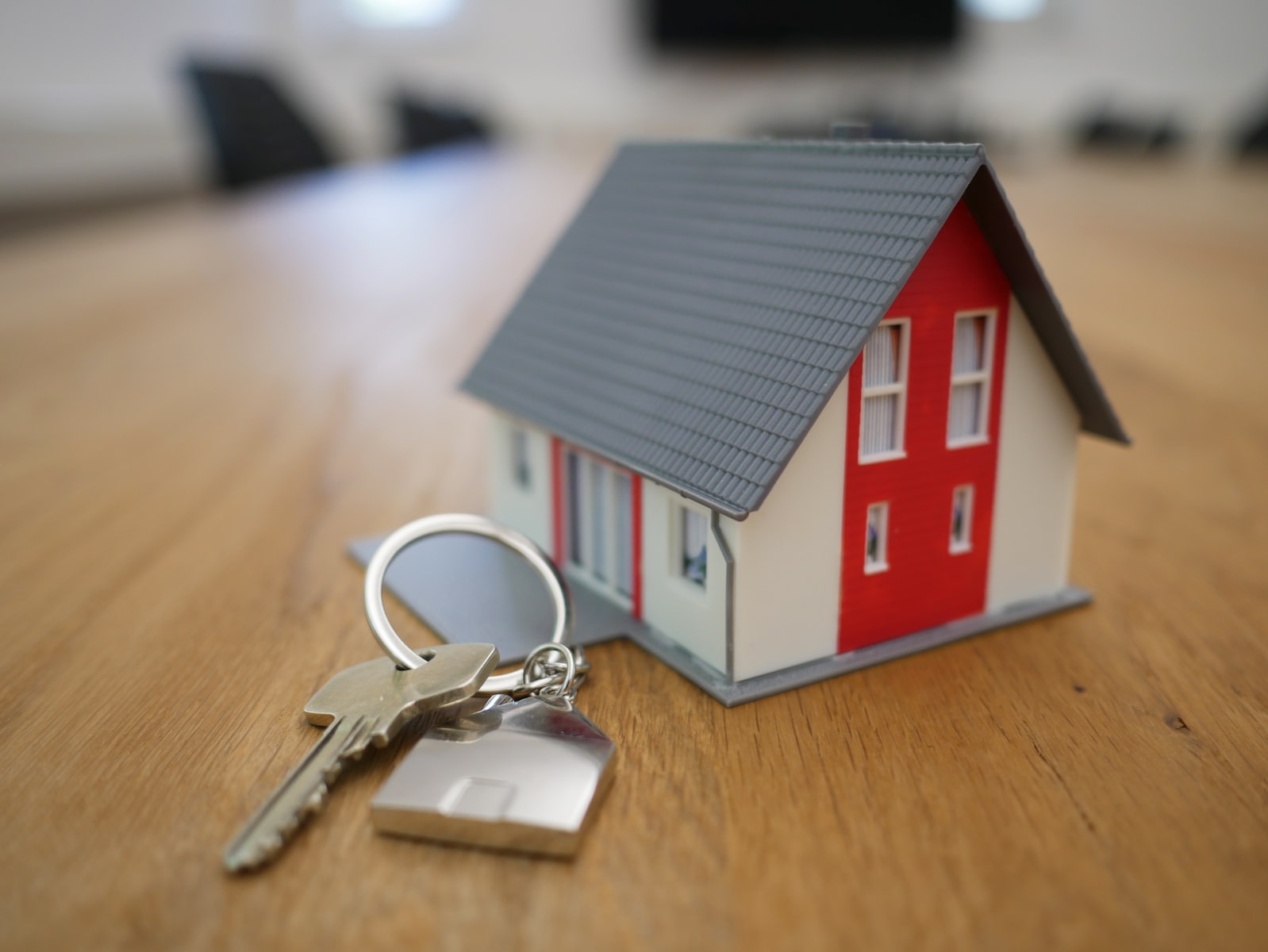 White and red wooden house miniature on brown table with keys